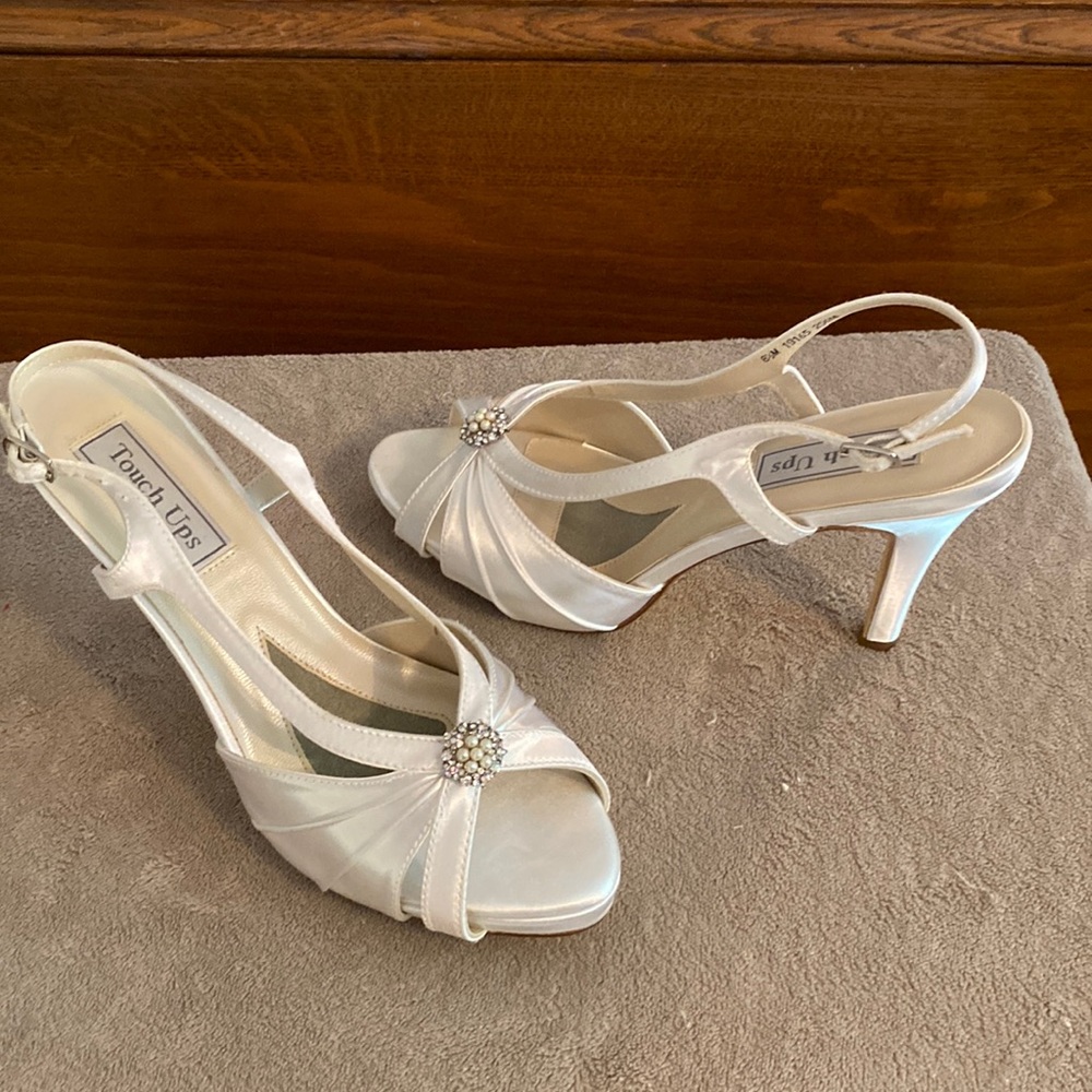 White satin sandal in an 8 an 1/2. The shoe has a 3 inch heel and an ornament